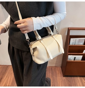Detail of cream pleated boston bag showing wavy texture and gold metal hardware