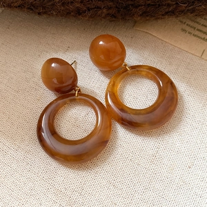 Macro detail of amber resin drop earrings featuring round beads on a linen texture background