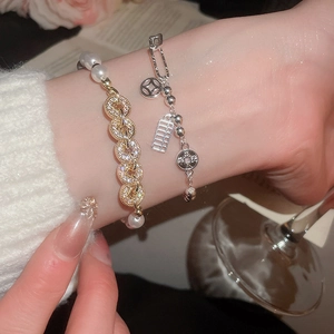 Detail of elegant stacked bracelets with pearls, zircons and Chinese coin charms