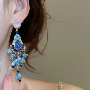 Detail of vintage bohemian style drop earrings featuring blue crystals and gold setting