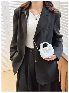 Detail of white micro chain bag with silver handle held by a model in soft light