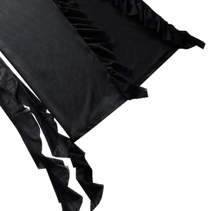 Detail of black dress featuring ruffled edges and hanging tie design on soft fabric