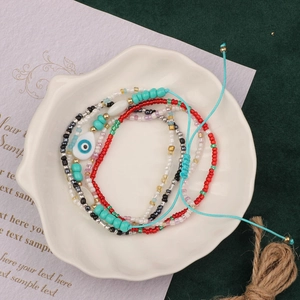 Detail of colorful handmade beaded bracelet with evil eye charm in a ceramic dish