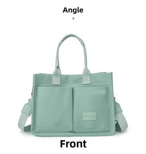Detail of mint green canvas tote bag featuring double front pockets and adjustable strap
