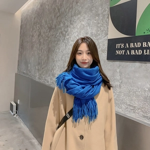 Thick blue cashmere knit scarf with fringe tassels shown on a female model in winter coat