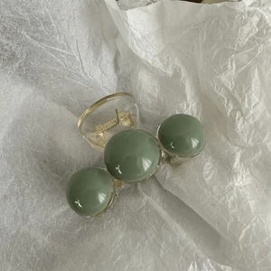 Detail of green candy-colored beads on a transparent hair claw clip with metal spring