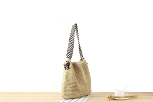 Detail of paper rope woven tote bag with nautical striped strap on wooden desk