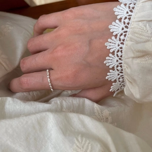 Detail of adjustable silver chain ring with beaded texture on model's finger