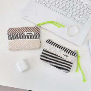 Detailed view of woven striped cosmetic pouches with vibrant green lanyards on a desk
