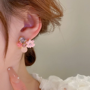 Close-up of a floral earring with pink cat-eye stone and crystal on a model's ear
