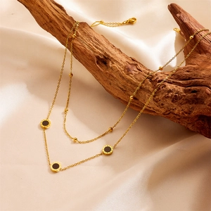 Detail of gold double-layer necklace with black shell pendants and Roman numerals