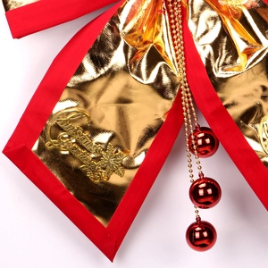 Red and gold Christmas bow ornament with metallic bells and sequins on white background