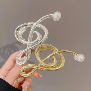 Detailaufnahme der Musiknoten-Haarklammer aus Metall mit Perle in Gold und Silber