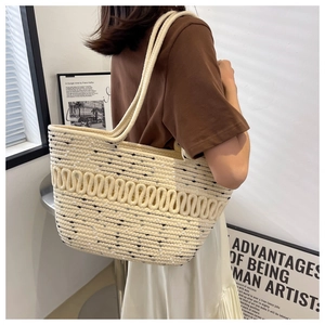 Side view of a large woven tote bag in cream white worn by a model in a minimalist room