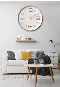 Modern wall clock with rose gold frame and 3D numerals in a minimalist living room