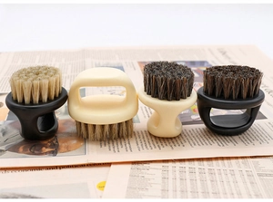 Detail view of four vintage finger ring beard brushes with boar bristles on old newspaper