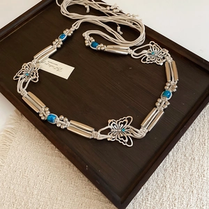 Detail view of woven bohemian belt with turquoise beads and butterfly charms