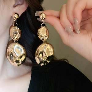 Detailed view of gold triple layered hammered oval earrings worn by a model