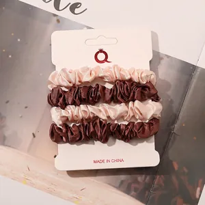 Detail of 4-pack satin scrunchies in champagne and brown on a white display card