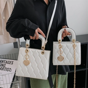 Glossy white quilted patent leather lady handbag with golden chain and heart charm pendant