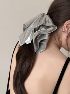 Close-up of metallic silver oversized scrunchie with pleated texture on high ponytail