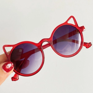 Close-up of red cat-ear children's sunglasses with purple gradient round lenses.