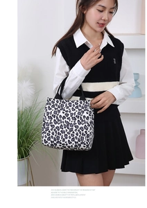 Detail shot of black and white leopard print canvas tote bag held by a fashion model