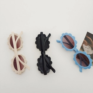 Kids flower-shaped oval sunglasses in beige black and blue on a minimal background