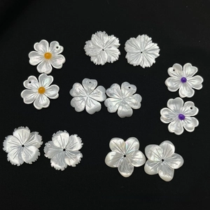 Macro detail of hand-carved white shell flower charms with pearlescent petal texture