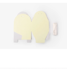 Flat lay of unassembled minimalist gift box with light yellow cardstock and white ribbon