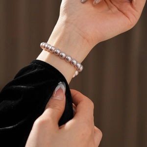 Close-up of elegant lavender pearl bracelet worn on wrist with black velvet sleeve detail