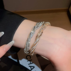 Close-up of elegant gold and silver multi-layer twisted bracelets with sparkling rhinestones