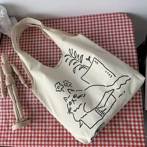 Detail of canvas tote bag featuring cute cat and plant illustration on red checkered fabric