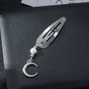 Silver metal hair clip with pearl and crescent moon pendant on black leather background