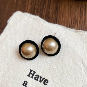Detail shot of vintage gold hemisphere earrings with black velvet trim on textured paper