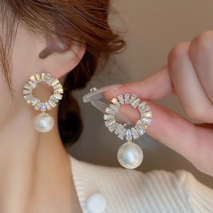 Detail of gold plated earring with radiant baguette crystals and a large white pearl
