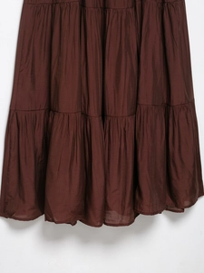Detail of tiered ruffled hemline on a brown layered maxi dress with soft fabric texture
