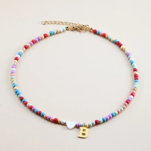 Detailed view of colorful beaded necklace with a white heart and golden letter B pendant