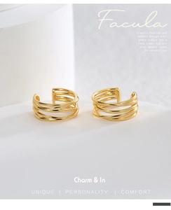 Close-up of gold plated multi-layer wrap ear cuffs on white textured stone background