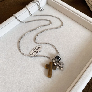 Detail of silver box chain necklace with tiger eye cross pendant on jewelry tray