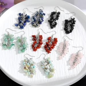 Close-up of handmade natural stone tassel earrings in various colors on a white plate