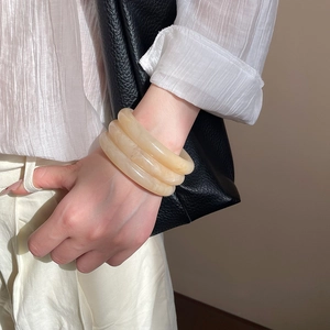 Close-up of three-layer cream resin geometric bangles worn on a woman's wrist