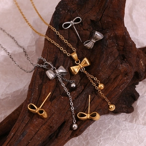 Golden and silver bow jewelry set with necklace and earrings on a rustic wood base