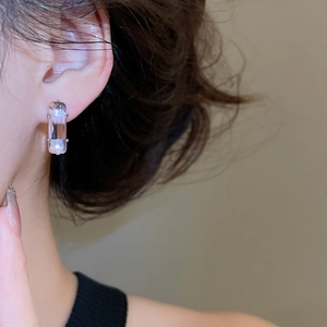 Close-up of minimalist rectangular pink zircon stud earrings with silver prong setting