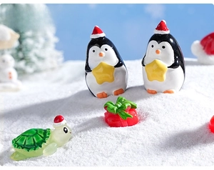 Macro shot of miniature Christmas penguin and turtle figurines in a snowy micro landscape