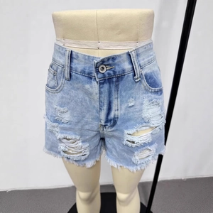 Close-up of ripped denim shorts featuring heavy distressing and frayed fringe hem details