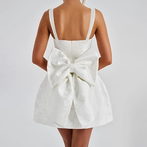 Détail d'une élégante robe mini en jacquard blanc avec un grand nœud au dos et du relief