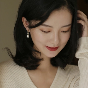 Elegant freshwater pearl drop earrings with gold metal accents worn by a female model