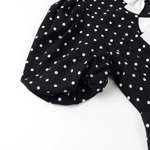 Close-up of black polka dot puff sleeves with a white bow detail and pleated cuff