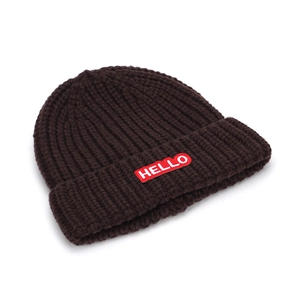 Détail du bonnet en maille marron foncé avec écusson brodé Hello rouge sur le revers